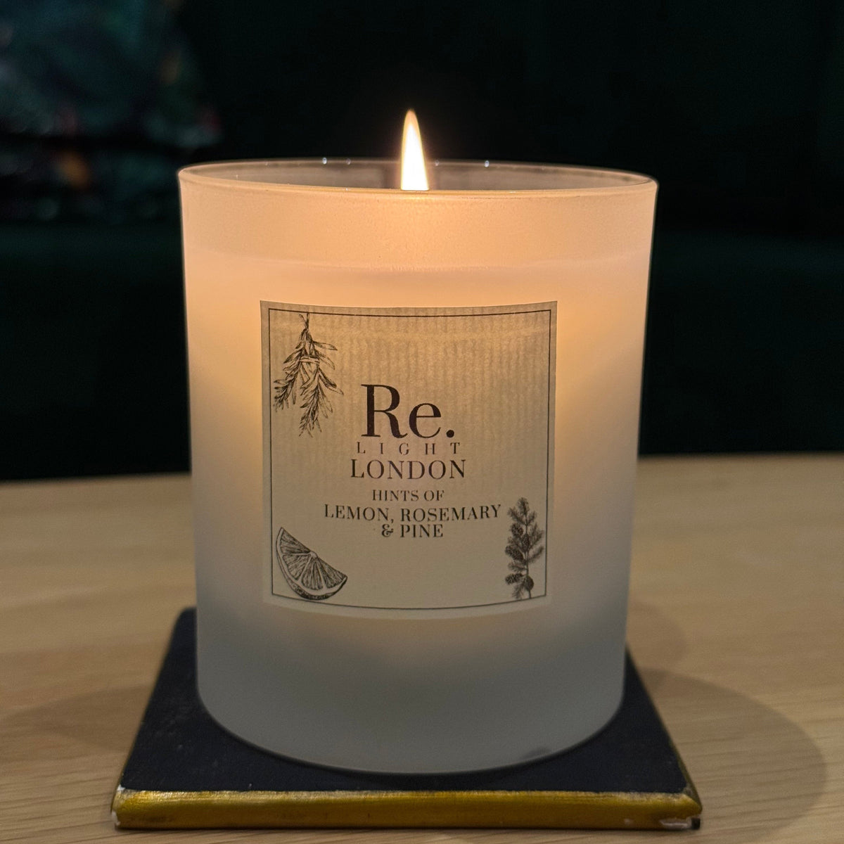 Candle with Re. label on coaster, set against a dark background