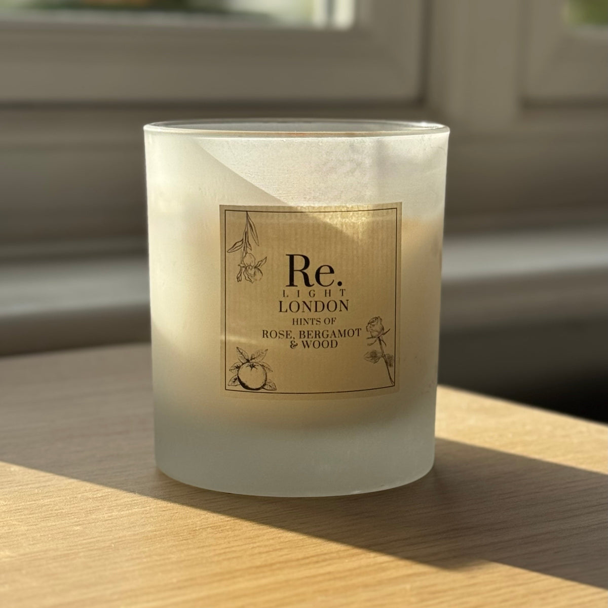 Re. frosted candle on a wooden surface, blurred window in the background